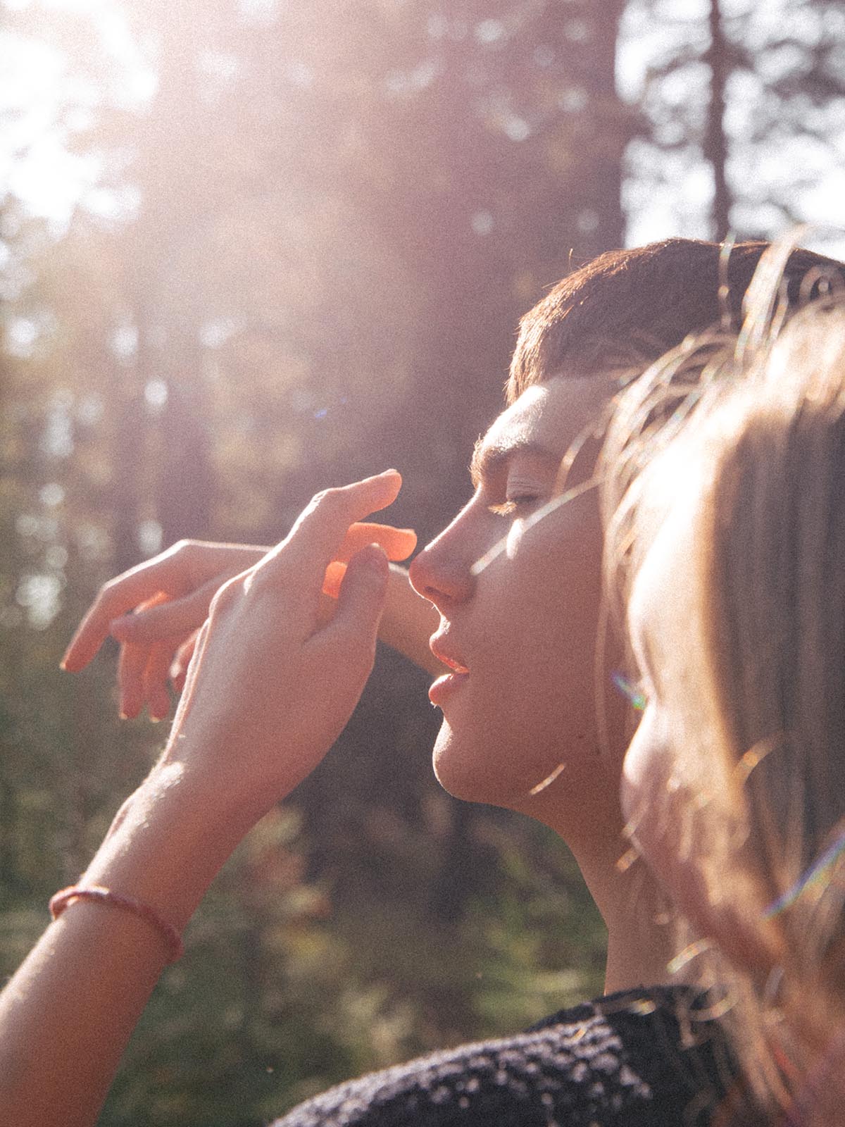 Mies taustavalossa koskettelee aknettomia kasvojaan